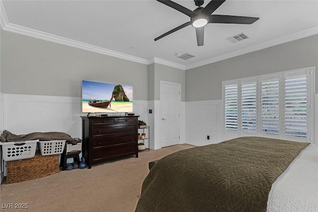 carpeted bedroom featuring ornamental molding, wainscoting, visible vents, and ceiling fan