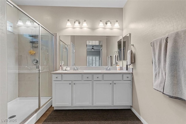 bathroom featuring double vanity, a stall shower, and a sink