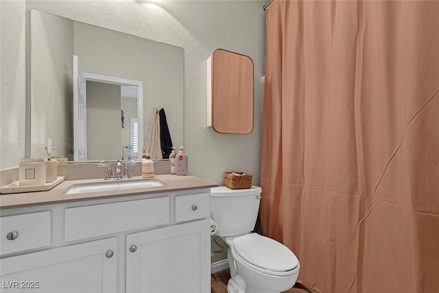 bathroom featuring a textured wall, curtained shower, vanity, and toilet