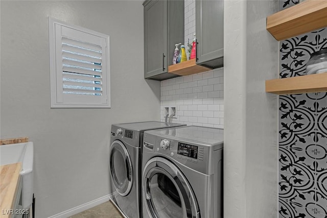 clothes washing area with independent washer and dryer, cabinet space, and baseboards