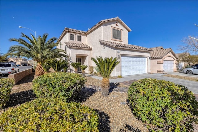 mediterranean / spanish-style house with a garage, concrete driveway, a tile roof, and stucco siding