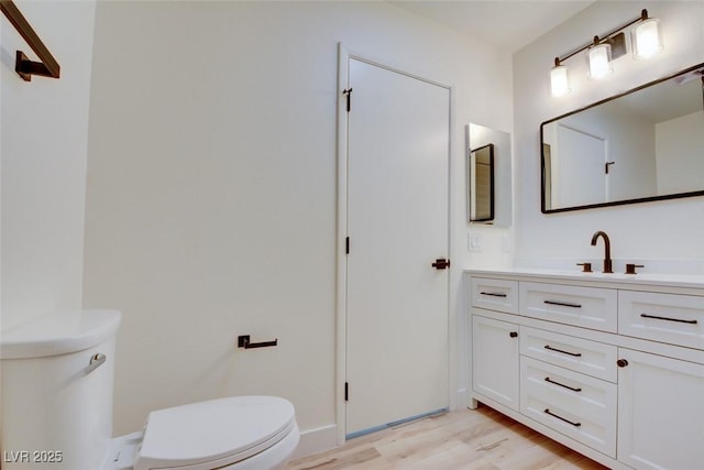 bathroom featuring toilet, wood finished floors, and vanity