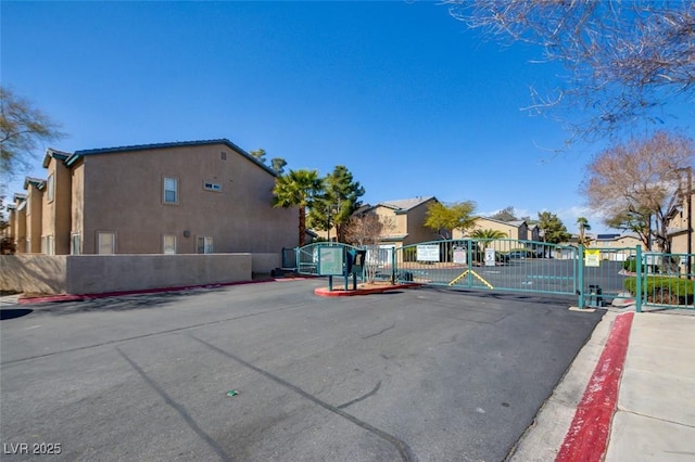 view of street with a residential view, a gated entry, curbs, a gate, and sidewalks