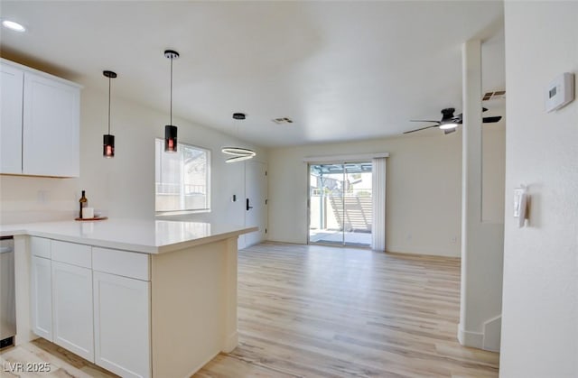 kitchen featuring open floor plan, a peninsula, light wood-style floors, white cabinetry, and pendant lighting