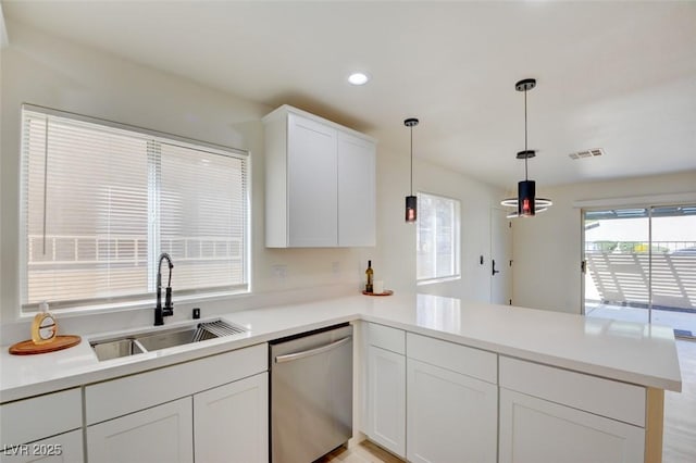 kitchen with a peninsula, dishwasher, light countertops, and a sink