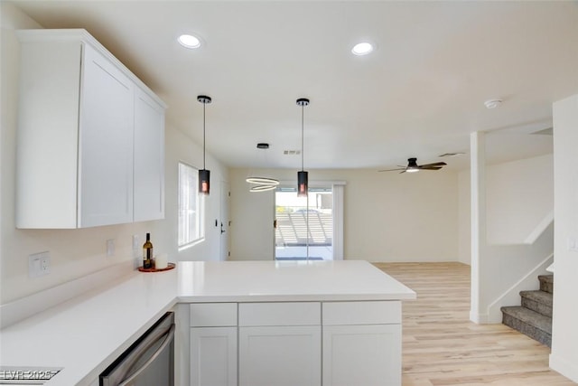 kitchen with a peninsula, white cabinetry, light wood-style floors, hanging light fixtures, and dishwasher