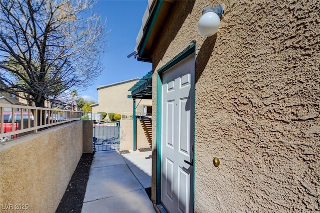 entrance to property with fence, a gate, a residential view, and stucco siding