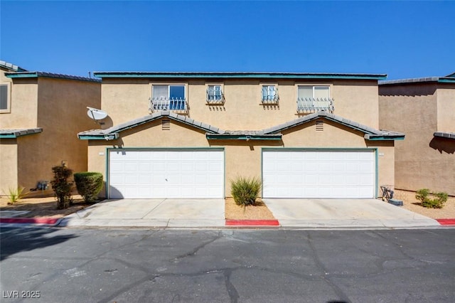 townhome / multi-family property featuring a garage, driveway, and stucco siding