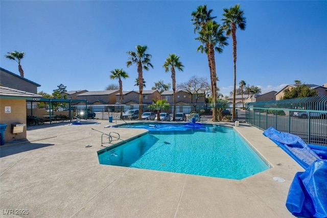 pool with a patio area, a residential view, and fence