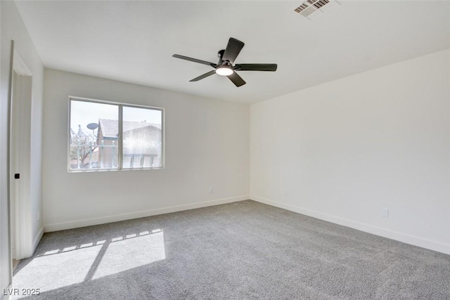 spare room with carpet floors, a ceiling fan, visible vents, and baseboards