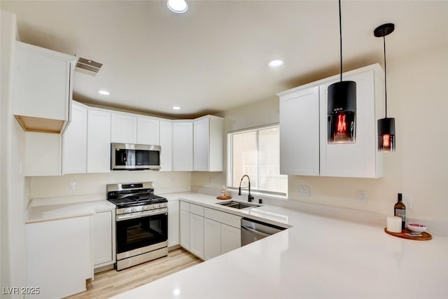 kitchen featuring appliances with stainless steel finishes, light countertops, visible vents, and a sink