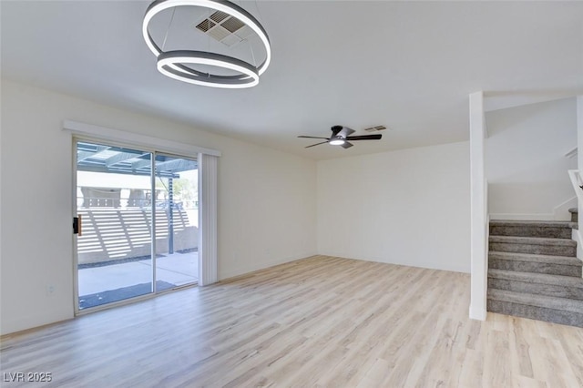 unfurnished living room featuring ceiling fan, stairs, visible vents, and wood finished floors