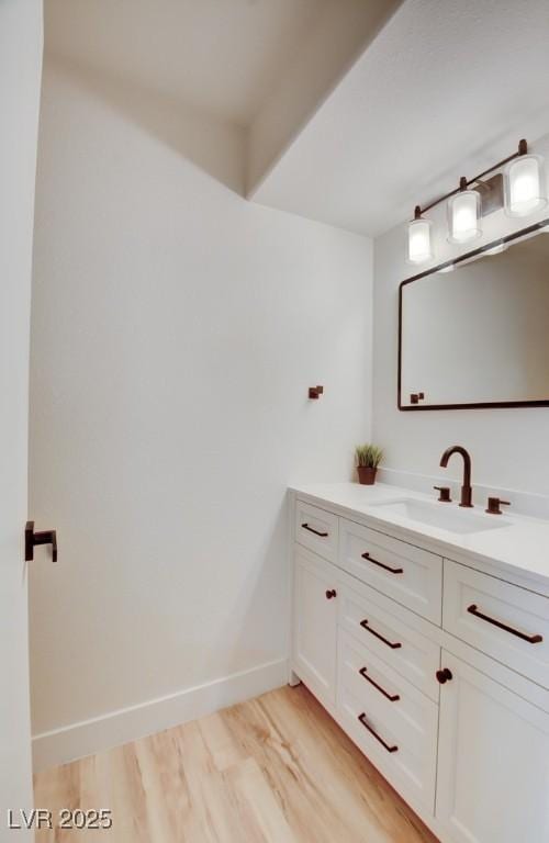 bathroom with wood finished floors, vanity, and baseboards