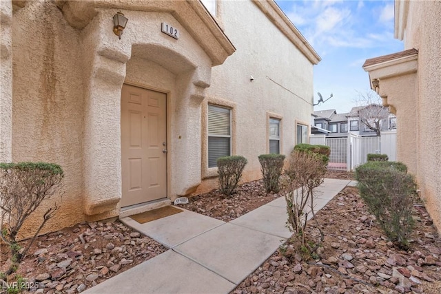 doorway to property with fence and stucco siding