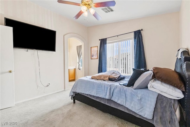 bedroom featuring ceiling fan, arched walkways, connected bathroom, light carpet, and visible vents