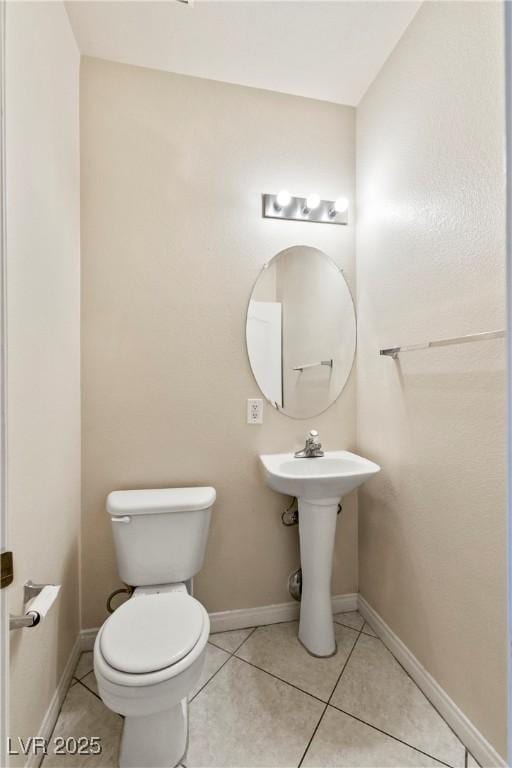 half bath featuring tile patterned flooring, baseboards, and toilet