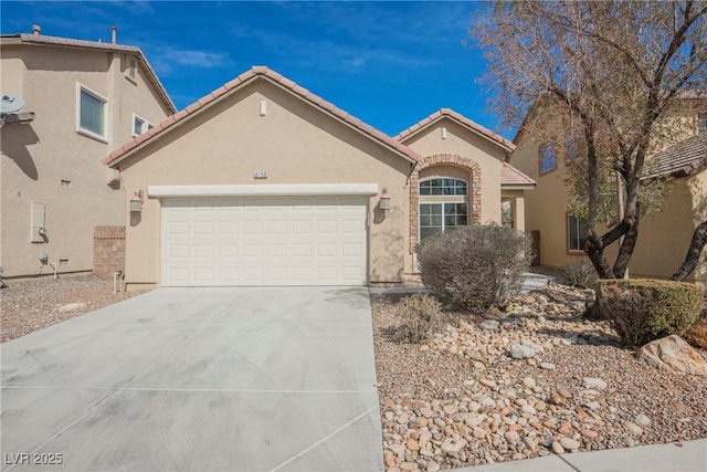 mediterranean / spanish home featuring concrete driveway, a tile roof, an attached garage, and stucco siding