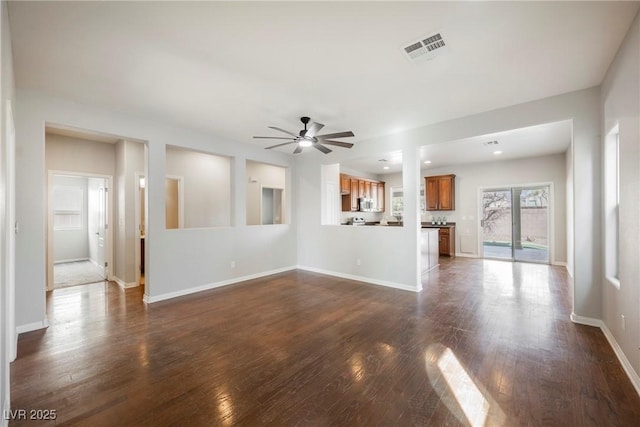 unfurnished living room with baseboards, visible vents, ceiling fan, and dark wood-style flooring