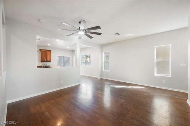 unfurnished living room featuring dark wood-type flooring, visible vents, ceiling fan, and baseboards