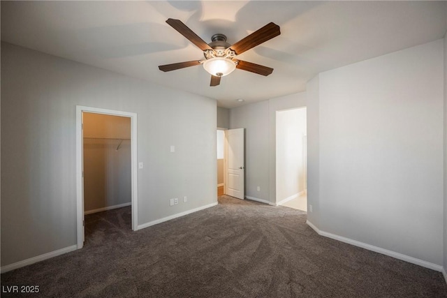 unfurnished bedroom with carpet flooring, a spacious closet, and baseboards