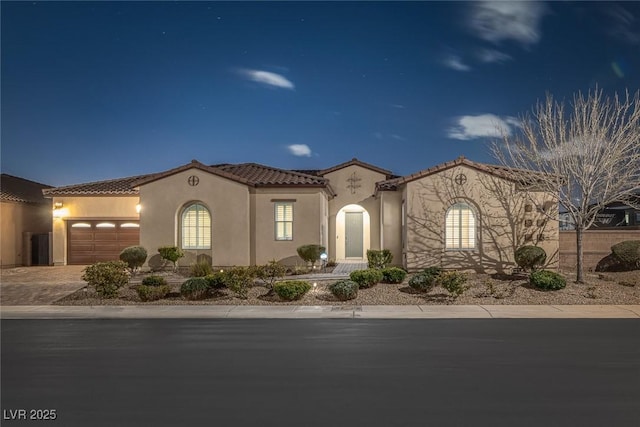 mediterranean / spanish home featuring an attached garage, a tiled roof, decorative driveway, and stucco siding