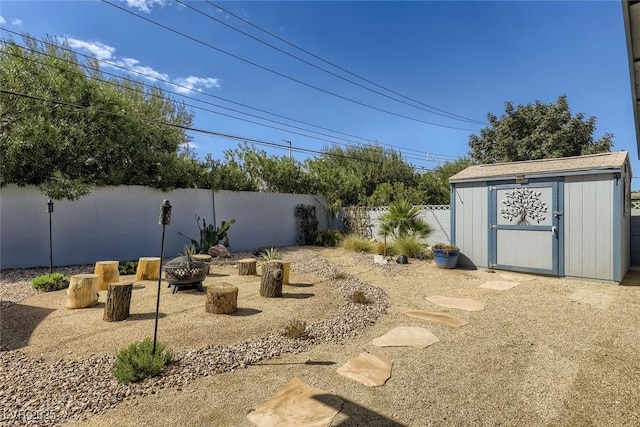 view of yard with an outdoor fire pit, a fenced backyard, an outbuilding, and a storage unit