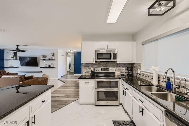 kitchen featuring stainless steel appliances, tasteful backsplash, a sink, and white cabinetry