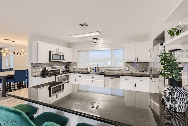 kitchen with white cabinets, backsplash, stainless steel appliances, and a sink