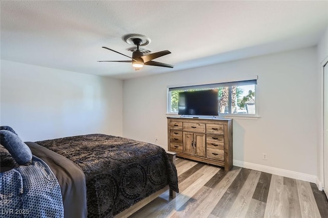 bedroom featuring a ceiling fan, light wood-style flooring, and baseboards