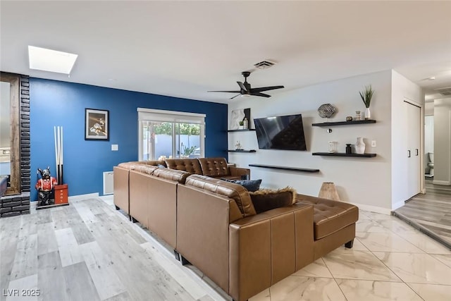 living area featuring marble finish floor, a skylight, visible vents, and baseboards