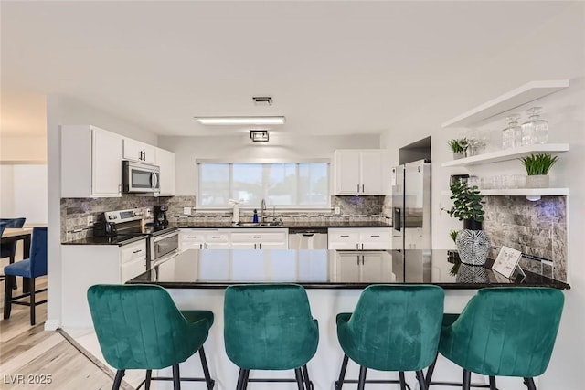 kitchen featuring appliances with stainless steel finishes, dark countertops, a sink, and a breakfast bar area