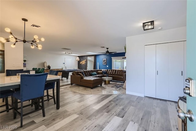 dining area featuring ceiling fan with notable chandelier, visible vents, and wood finished floors