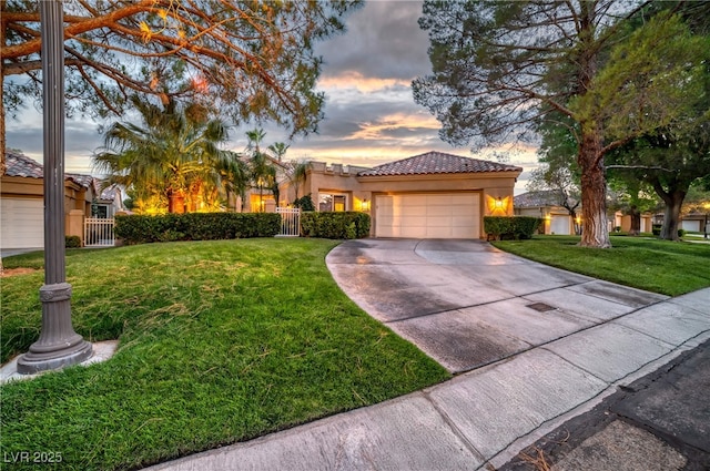 mediterranean / spanish house with driveway, a yard, a fenced front yard, and a tile roof