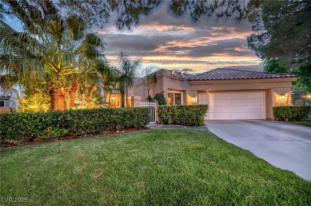 mediterranean / spanish home with a garage, concrete driveway, a yard, and stucco siding