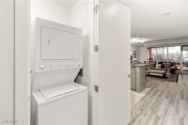 laundry area with stacked washer and dryer, laundry area, and light wood-style floors