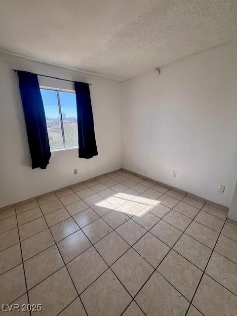 empty room with light tile patterned flooring and a textured ceiling