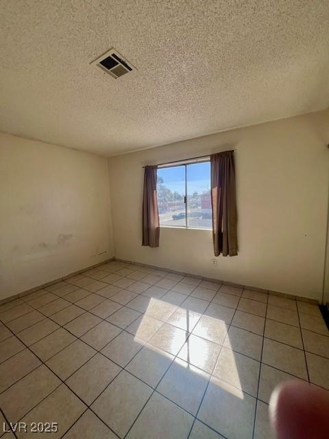 unfurnished room with visible vents, a textured ceiling, and light tile patterned floors