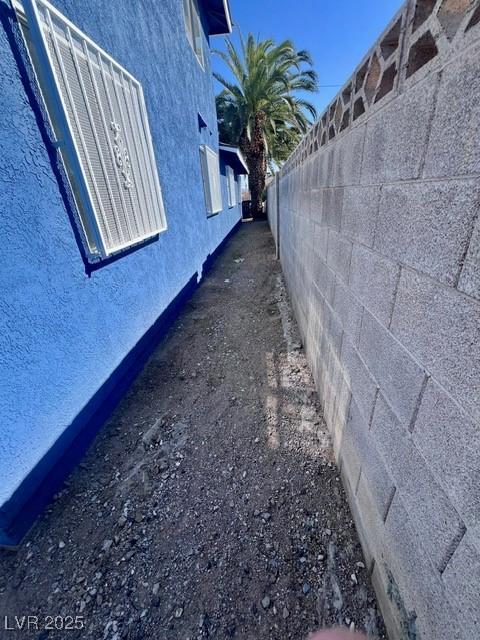 view of side of property featuring fence and stucco siding