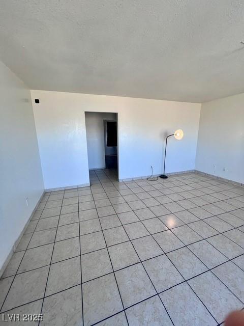 spare room with a textured ceiling and light tile patterned floors