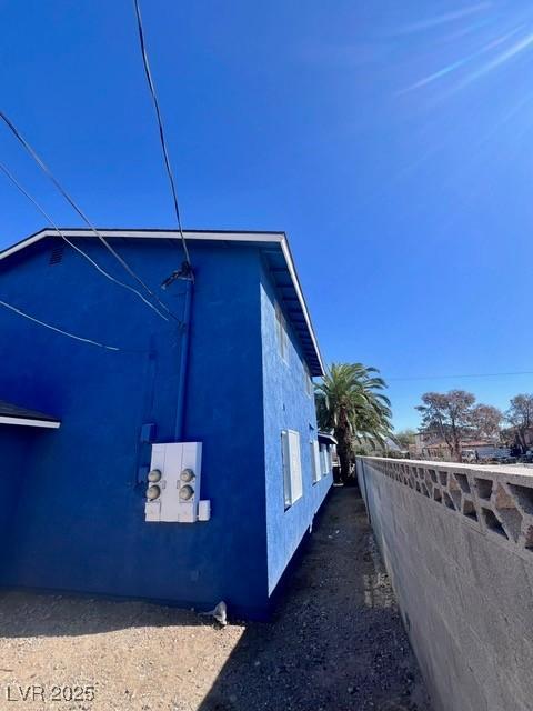 view of side of home with fence and stucco siding