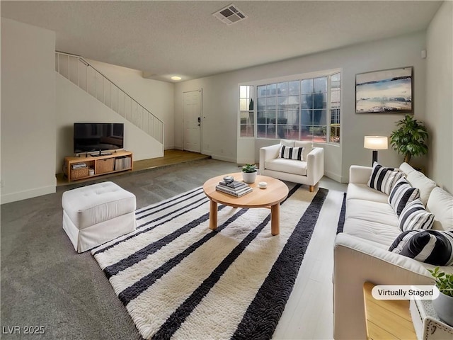 living room with visible vents, a textured ceiling, baseboards, and stairs