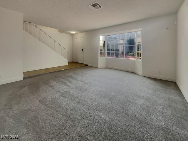 spare room featuring baseboards, visible vents, stairs, a textured ceiling, and carpet flooring