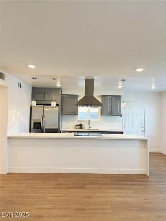 kitchen featuring light wood finished floors, stainless steel refrigerator with ice dispenser, visible vents, and island range hood