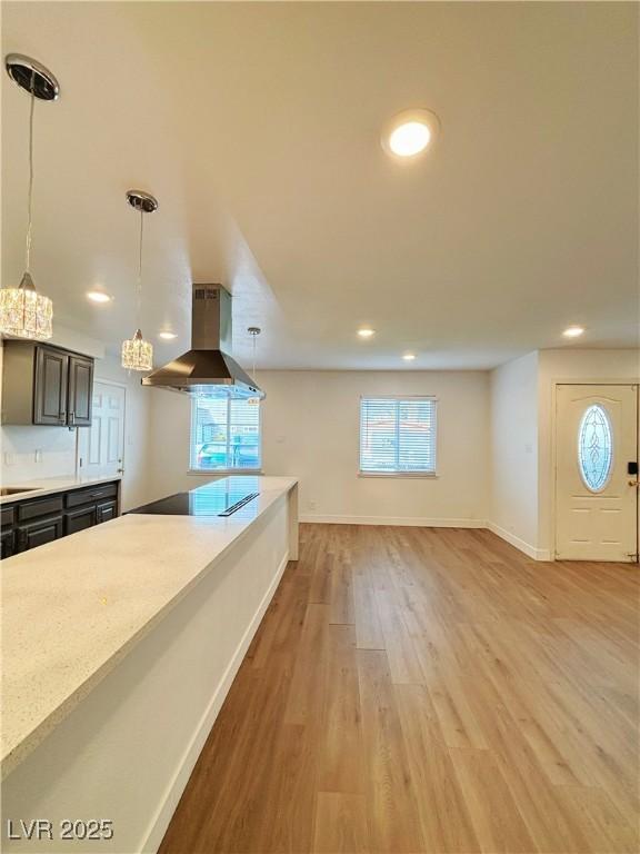 kitchen with baseboards, black electric stovetop, extractor fan, light wood-style floors, and pendant lighting