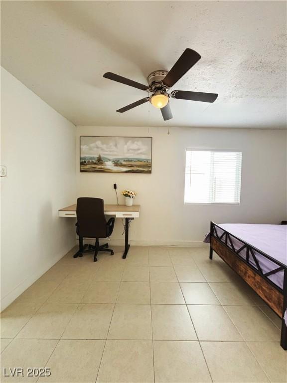 bedroom with light tile patterned floors, a textured ceiling, baseboards, and a ceiling fan