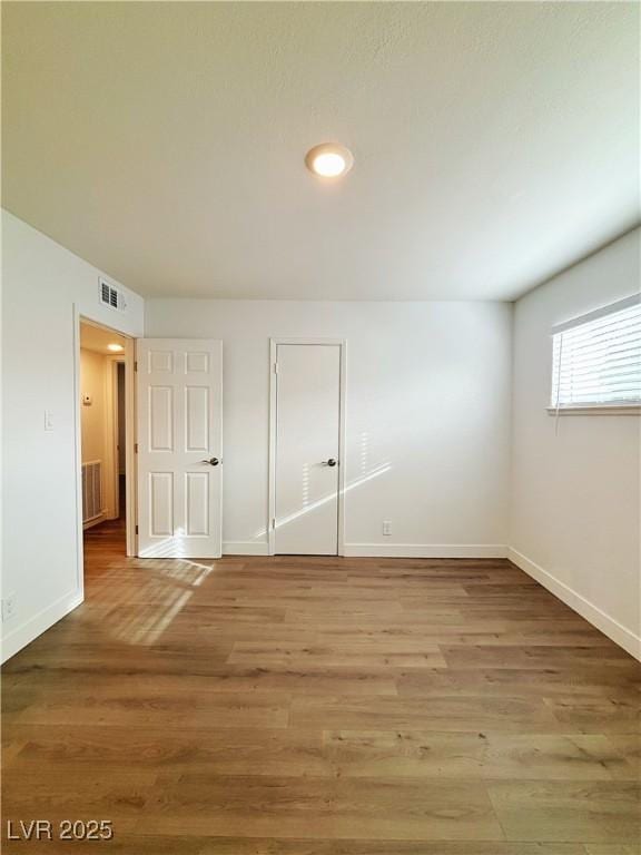 unfurnished bedroom with light wood-type flooring, visible vents, and baseboards