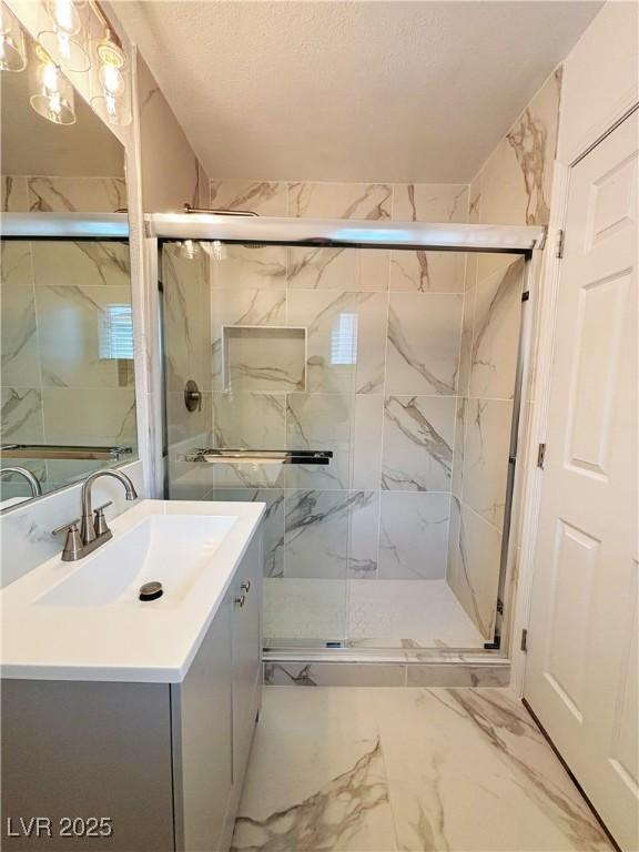 full bathroom with marble finish floor, a marble finish shower, a textured ceiling, and vanity