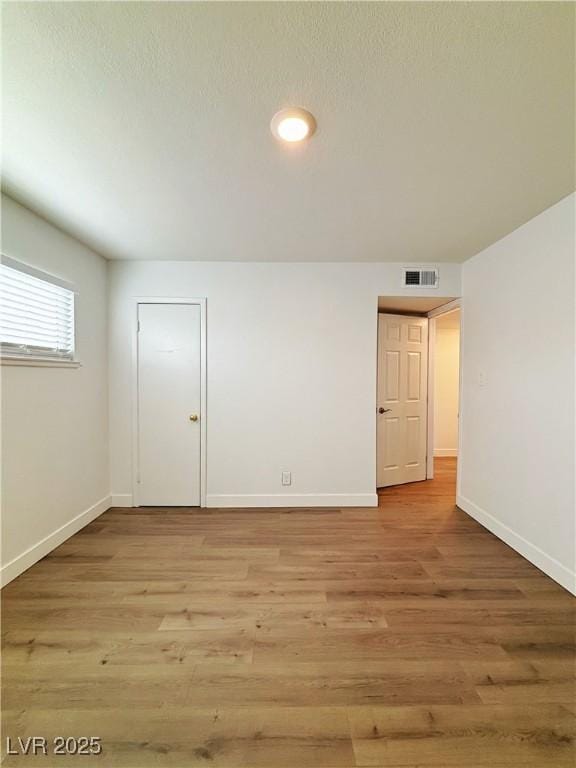 empty room featuring light wood-style flooring, visible vents, and baseboards