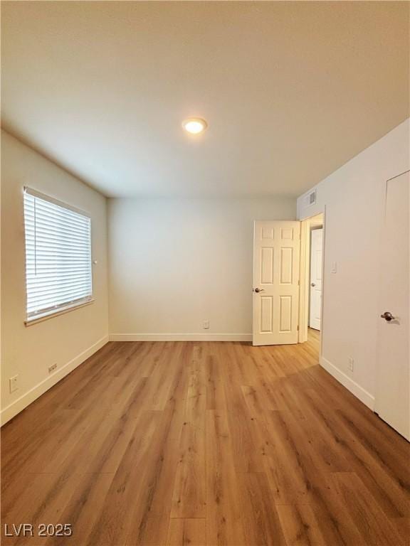 empty room with light wood-style flooring, visible vents, and baseboards