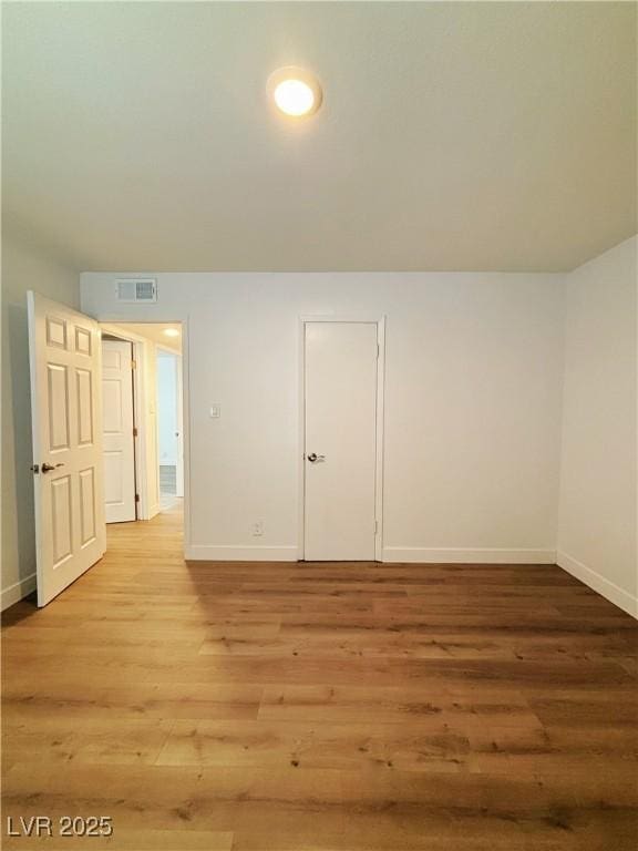 empty room featuring light wood-style flooring, visible vents, and baseboards